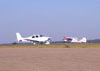 Cirrus SR-22 correndo para decolar e um Cessna 170-B, PT-APY, na taxiway.