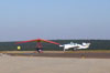 Uma Trike entrando na pista, e um Beechcraft Bonanza V35B na taxiway.