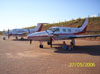 Dois voluntrios descansando embaixo da asa esquerda de um Piper PA-31T1 Cheyenne, PT-LRT. No fundo, um Beechcraft King Air F-90, PT-ONE.